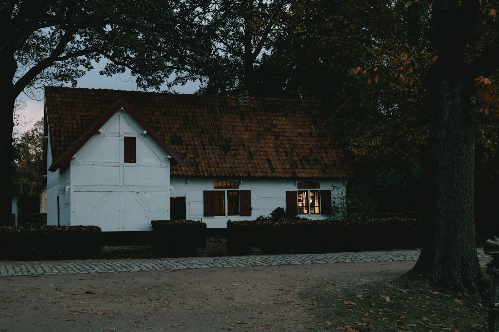 Helles Wohnhaus mit roten Fensterläden in der Abenddämmerung