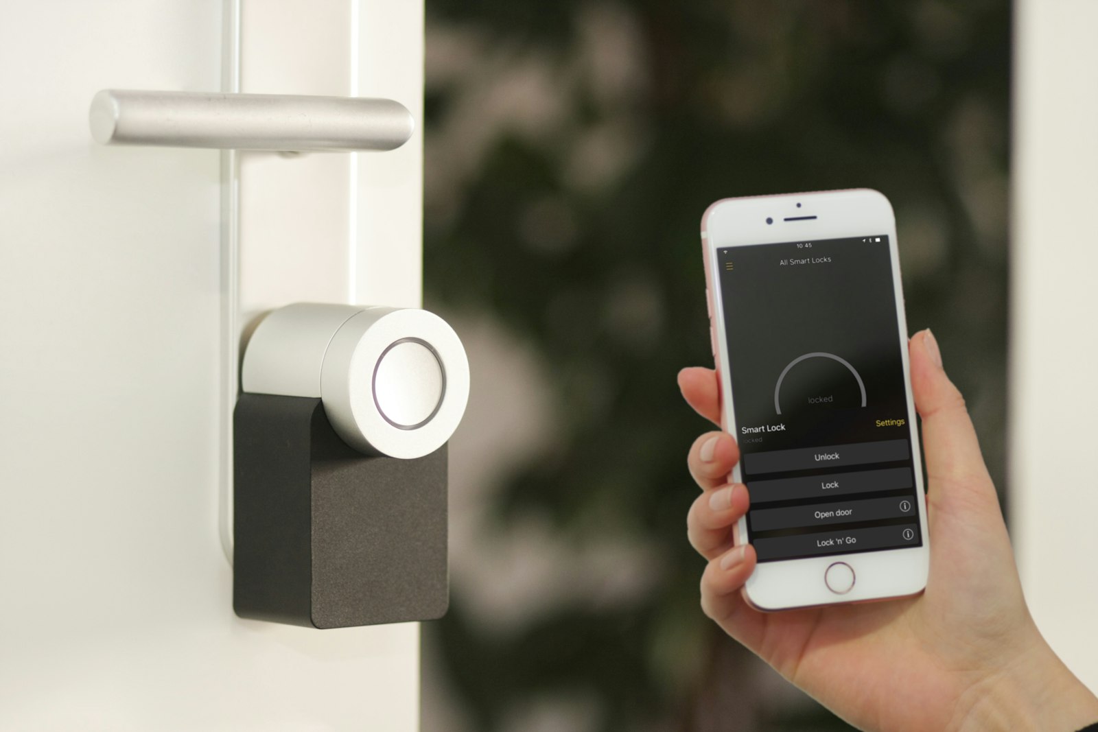 Elektronischer Türzylinder an einer Wohnungstür, daneben die Steuerung per Smartphone